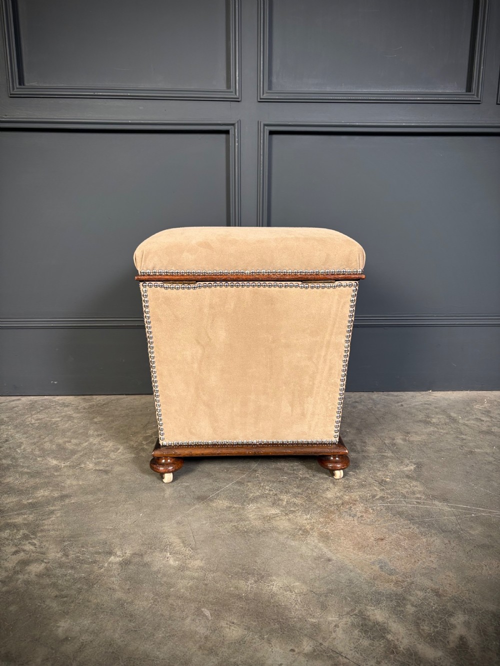 A pair of square Regency style ottomans upholstered in beige fabric with brass stud trimming, raised on short mahogany legs with castors. View XI