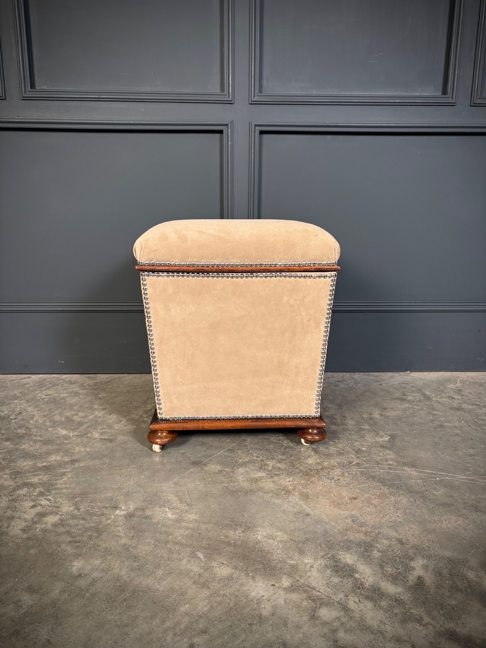 A pair of square Regency style ottomans upholstered in beige fabric with brass stud trimming, raised on short mahogany legs with castors. View XII
