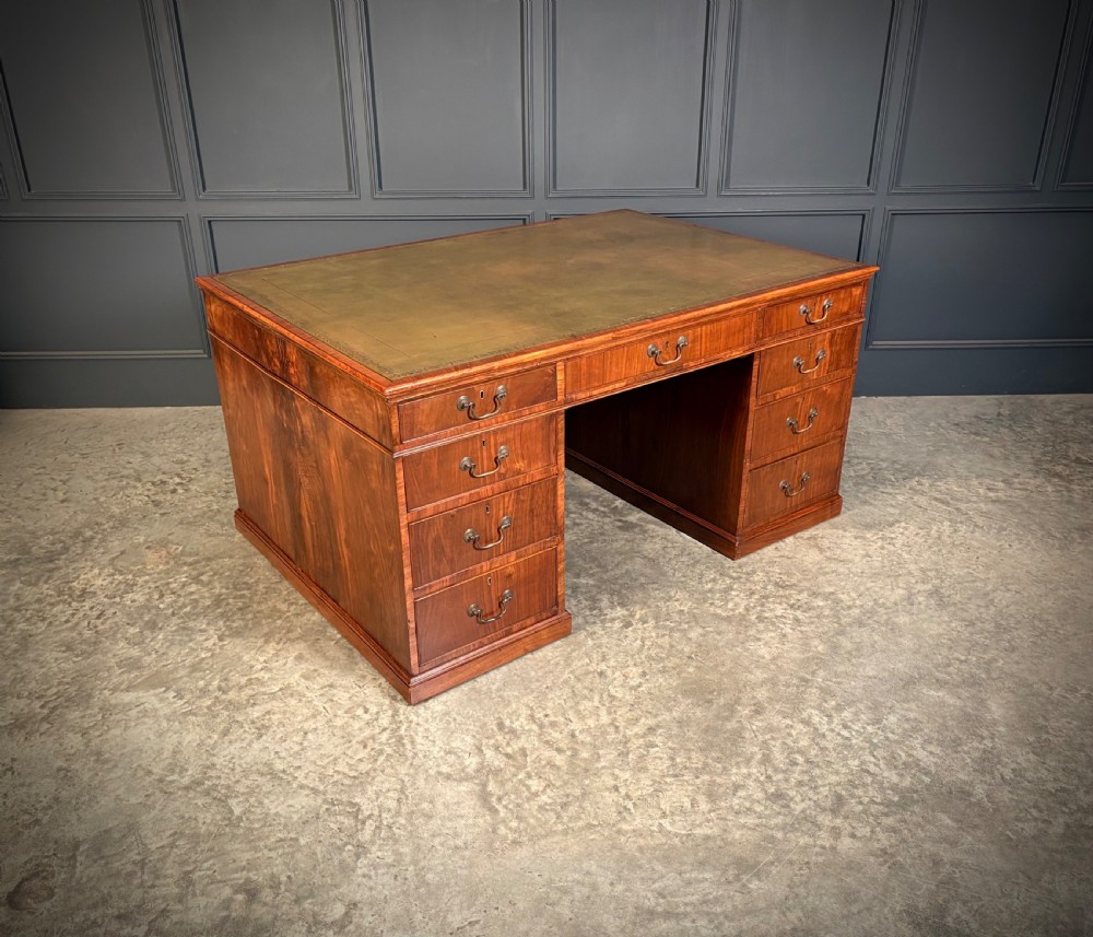 A large Victorian walnut partners desk featuring a green leather inset top, dual pedestals with multiple drawers, and brass handles. View XII
