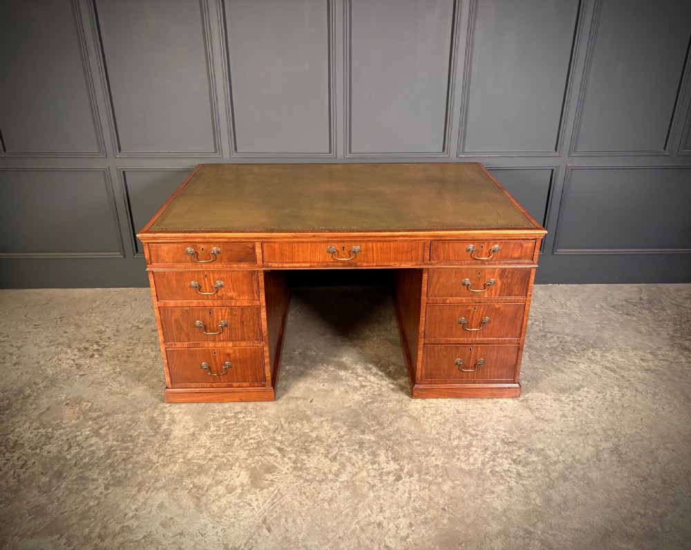 A large Victorian walnut partners desk featuring a green leather inset top, dual pedestals with multiple drawers, and brass handles. View III