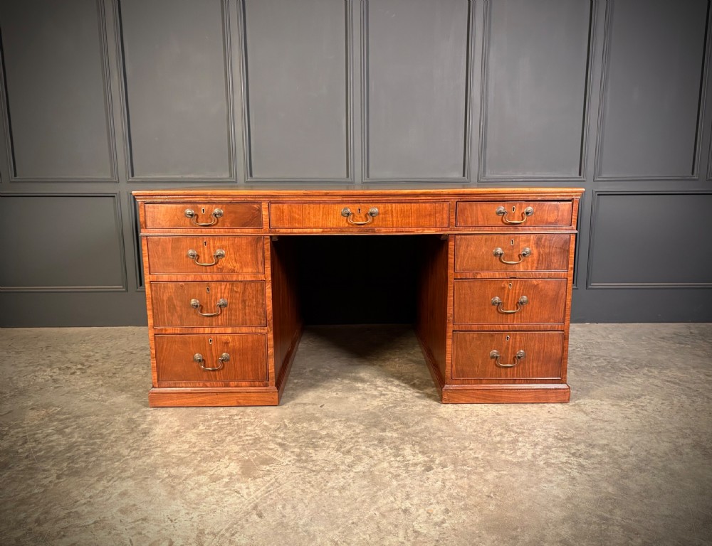 A large Victorian walnut partners desk featuring a green leather inset top, dual pedestals with multiple drawers, and brass handles. View IV