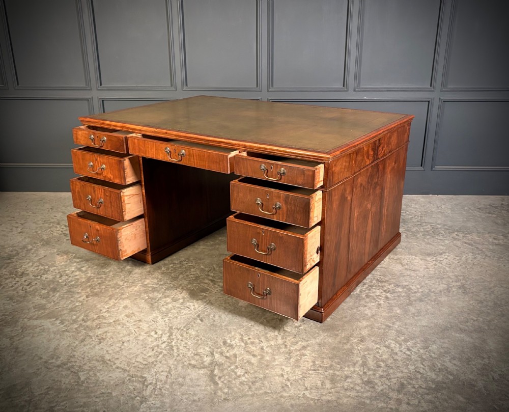 A large Victorian walnut partners desk featuring a green leather inset top, dual pedestals with multiple drawers, and brass handles. View V