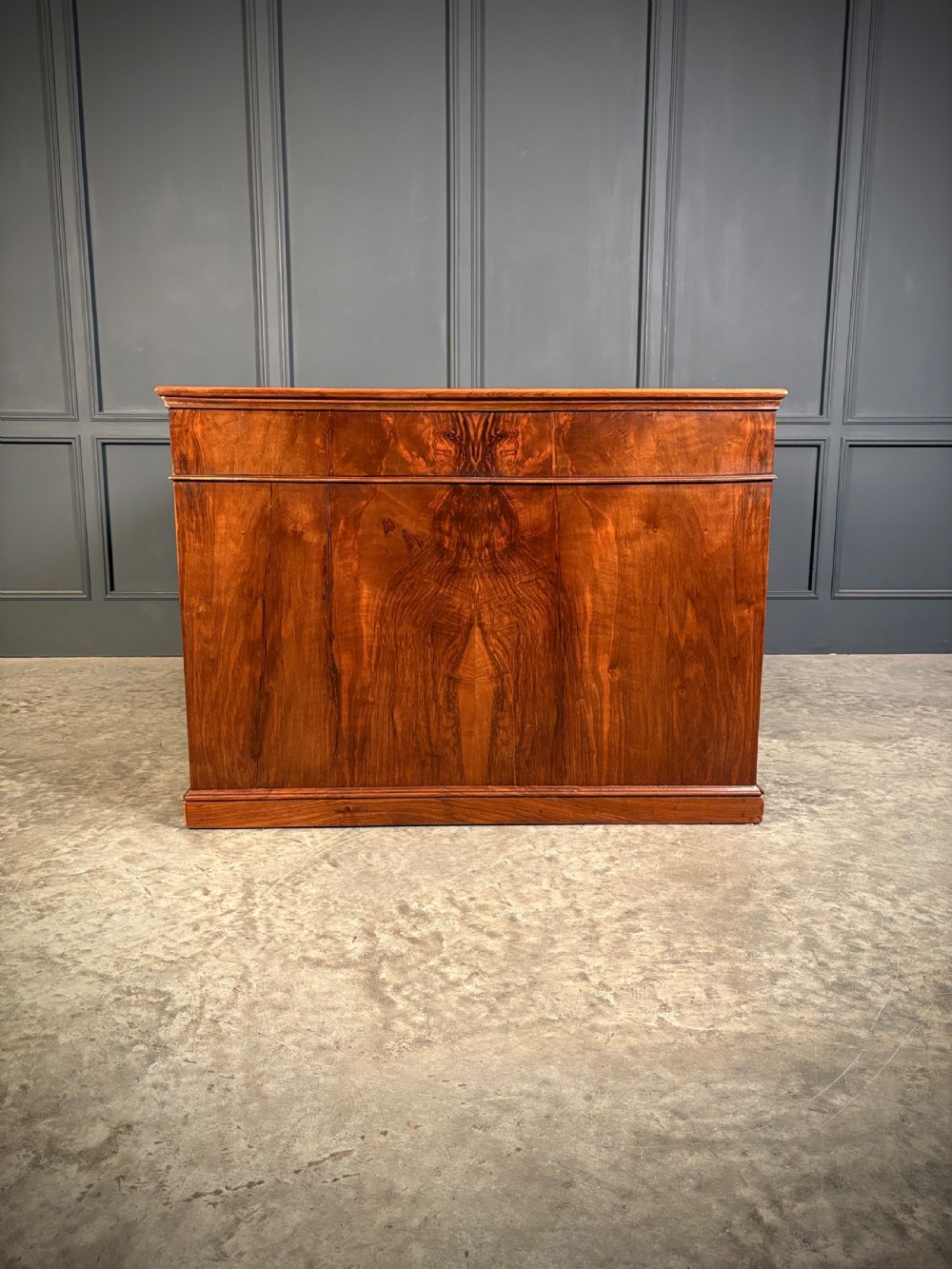 A large Victorian walnut partners desk featuring a green leather inset top, dual pedestals with multiple drawers, and brass handles. View VI