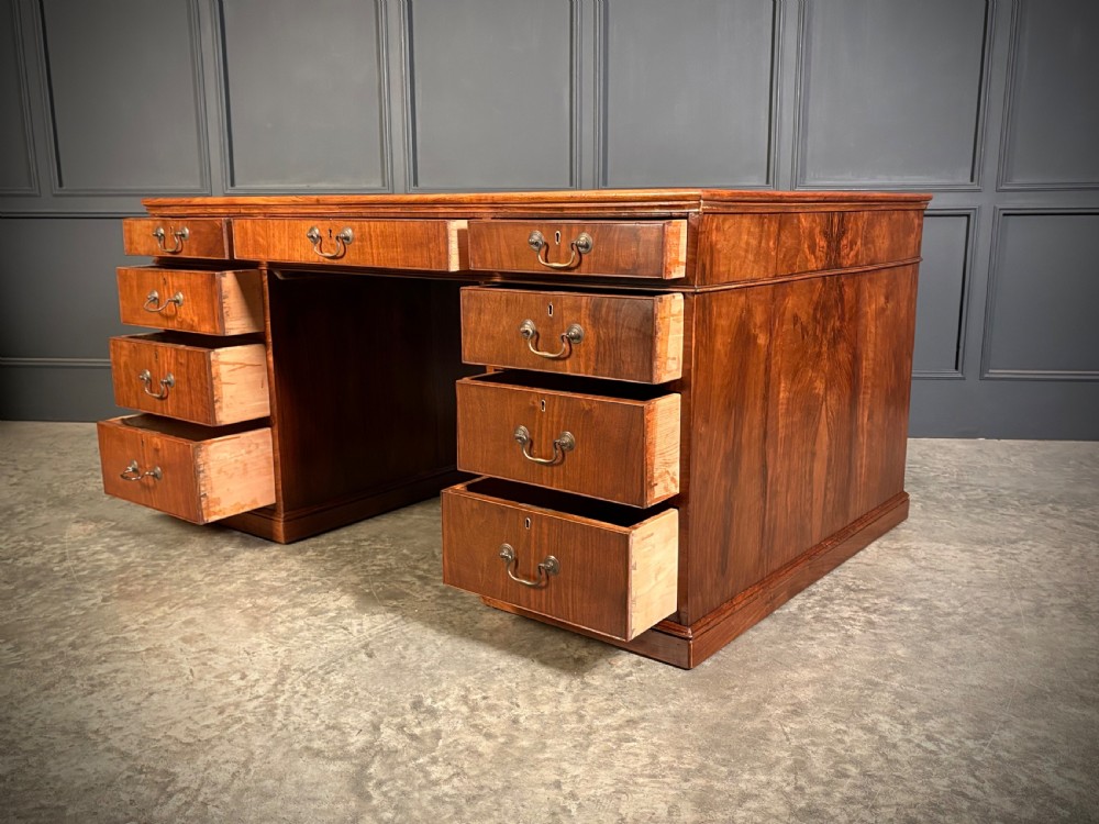 A large Victorian walnut partners desk featuring a green leather inset top, dual pedestals with multiple drawers, and brass handles. View VII