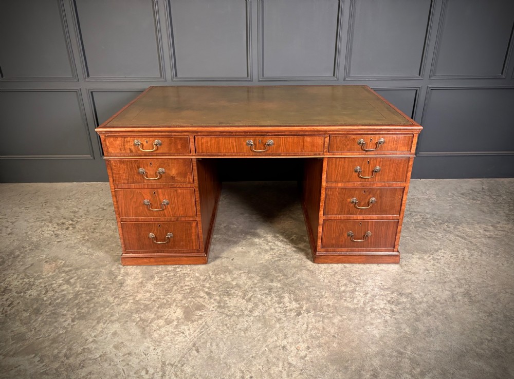 A large Victorian walnut partners desk featuring a green leather inset top, dual pedestals with multiple drawers, and brass handles. View VIII