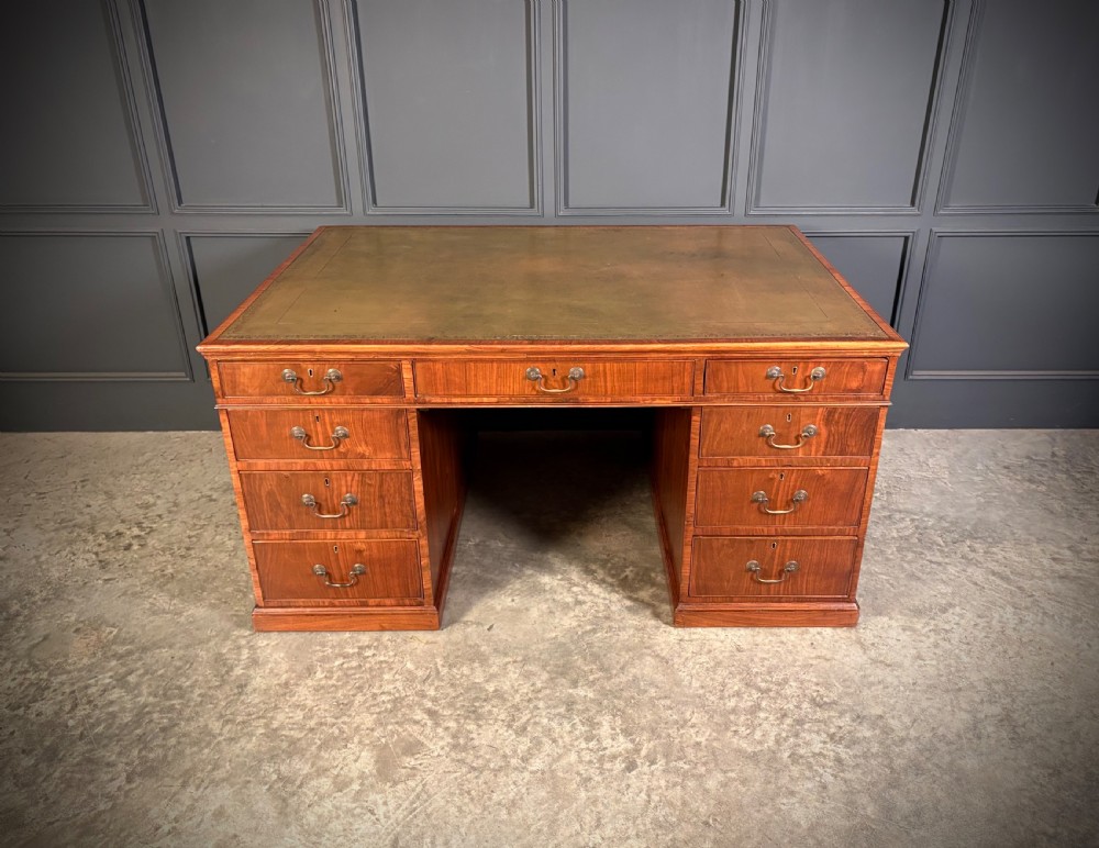 A large Victorian walnut partners desk featuring a green leather inset top, dual pedestals with multiple drawers, and brass handles.