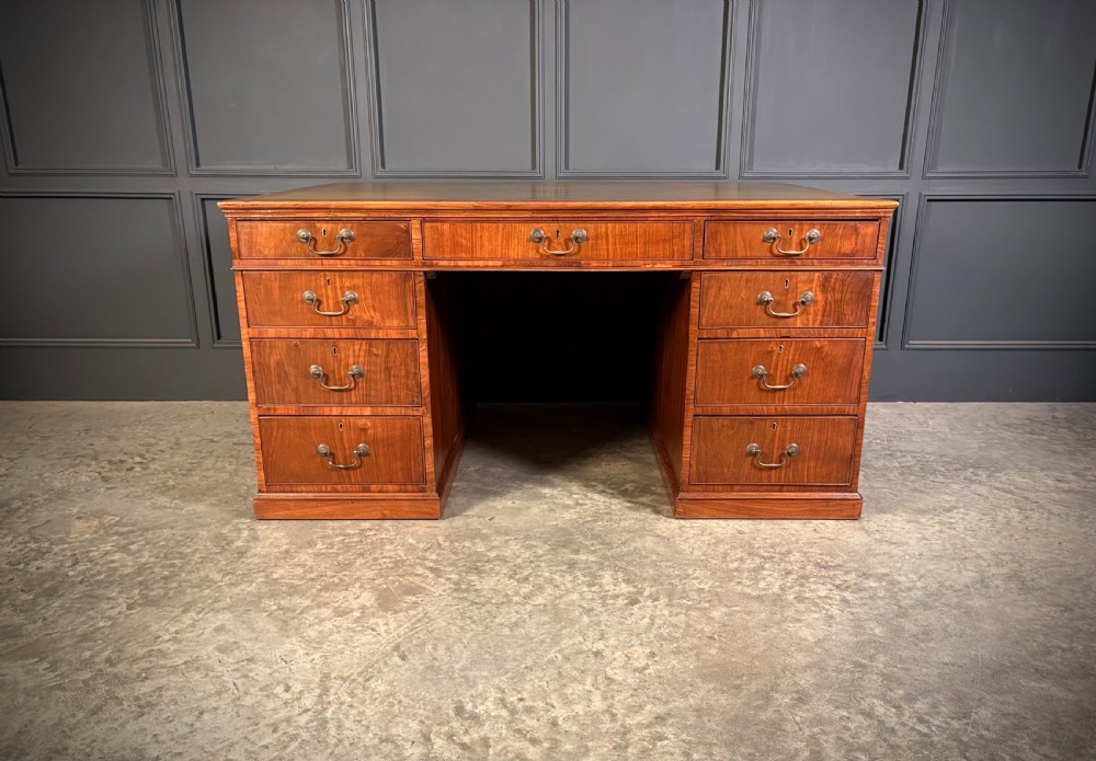 A large Victorian walnut partners desk featuring a green leather inset top, dual pedestals with multiple drawers, and brass handles. View XIV
