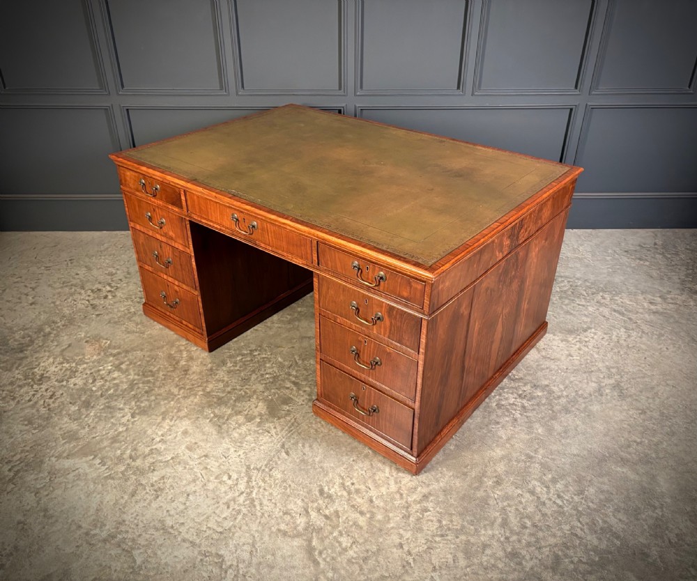 A large Victorian walnut partners desk featuring a green leather inset top, dual pedestals with multiple drawers, and brass handles. View XV