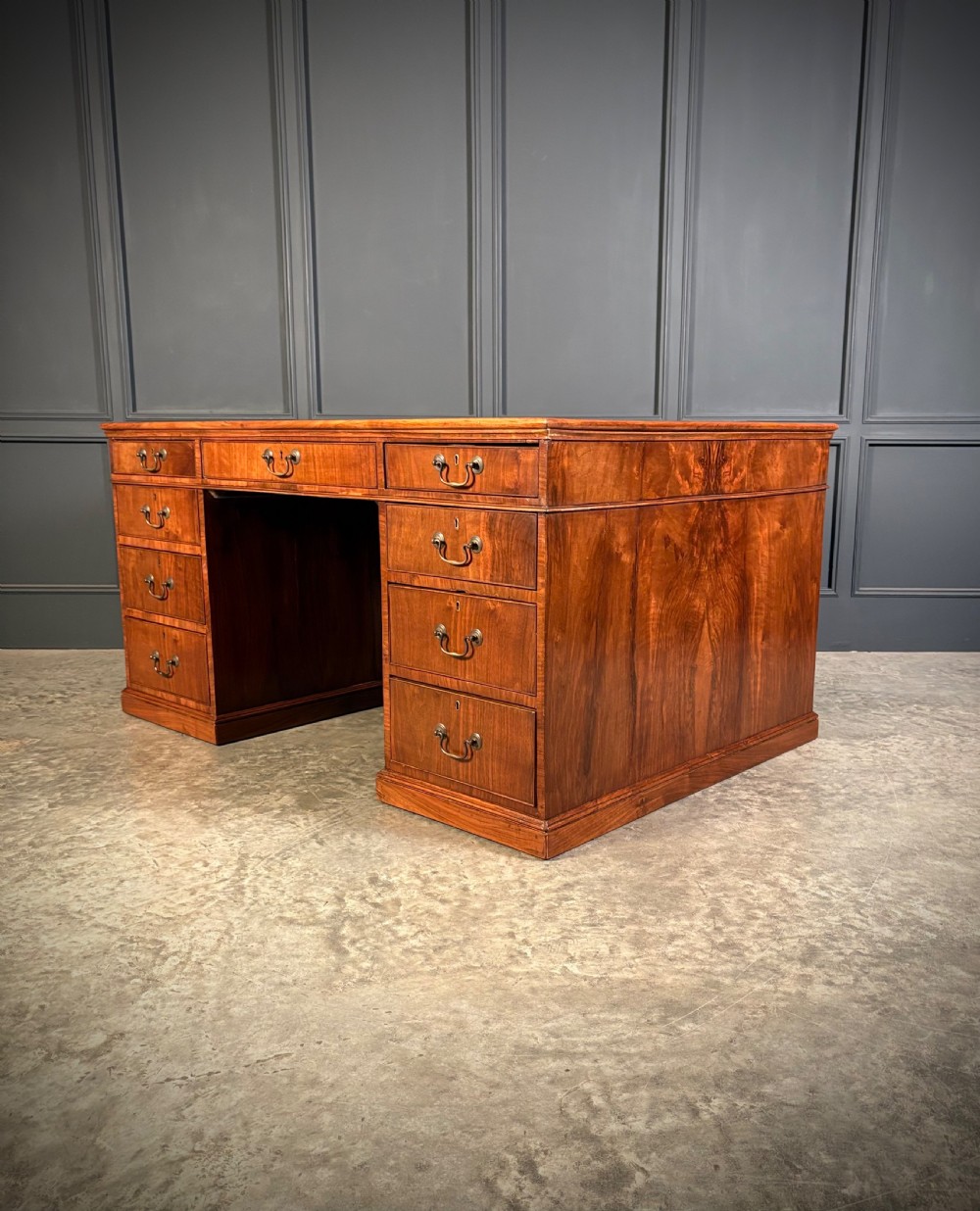 A large Victorian walnut partners desk featuring a green leather inset top, dual pedestals with multiple drawers, and brass handles. View XVI