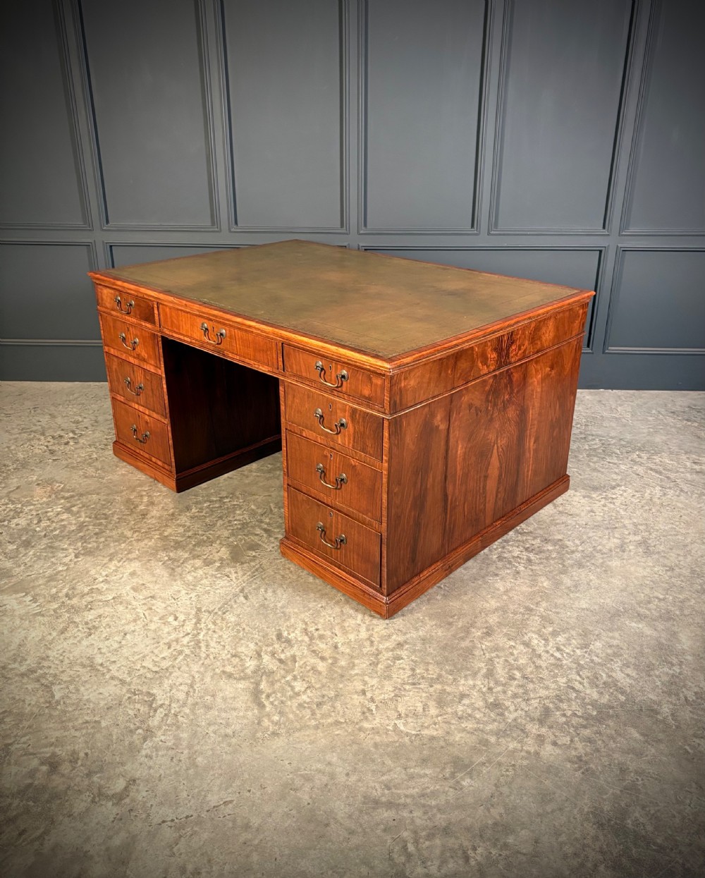 A large Victorian walnut partners desk featuring a green leather inset top, dual pedestals with multiple drawers, and brass handles. View XVII