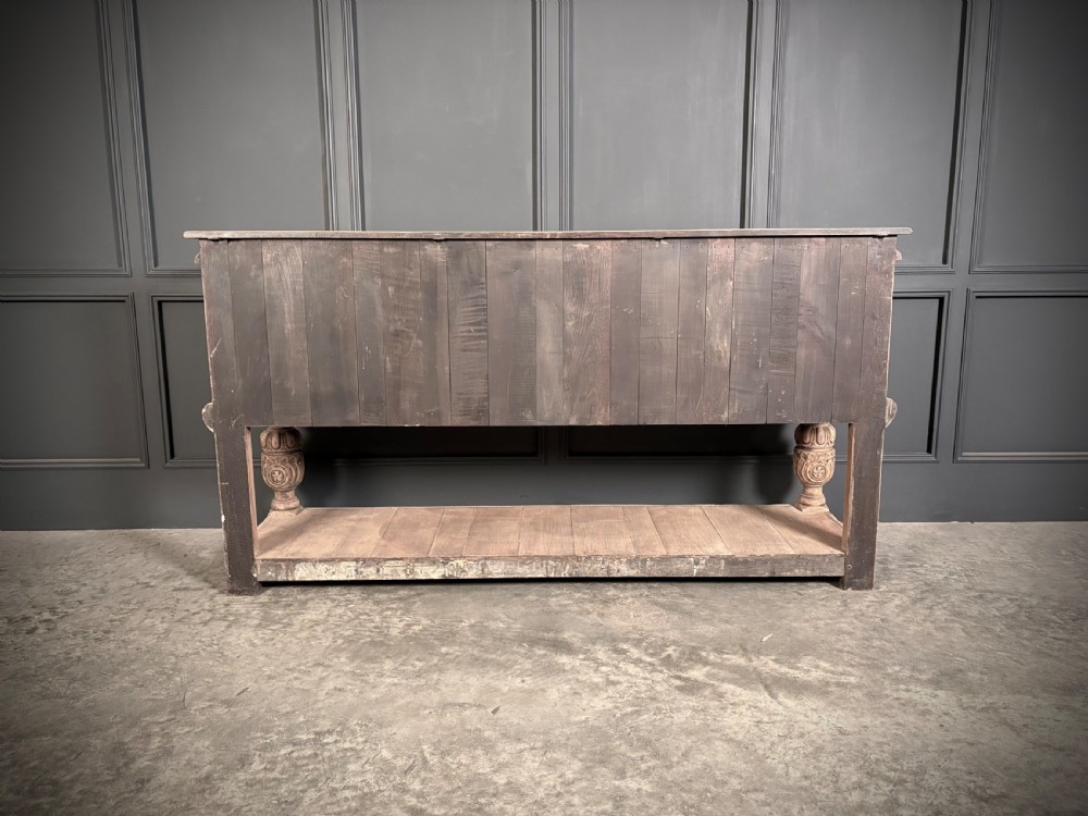A carved bleached oak sideboard featuring geometric relief panel doors, central drawers, turned front legs, and an open lower pot board shelf. View XVIII