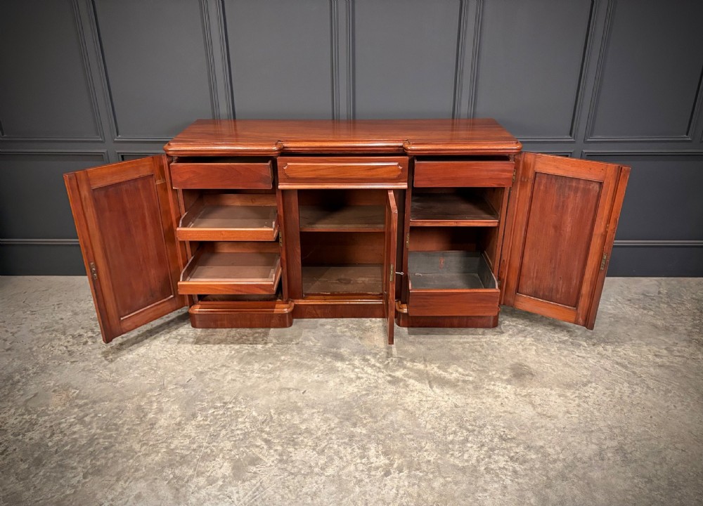 A Victorian mahogany three-door sideboard featuring flame mahogany panelled cupboard doors and a central top drawer on a solid plinth base. View VII