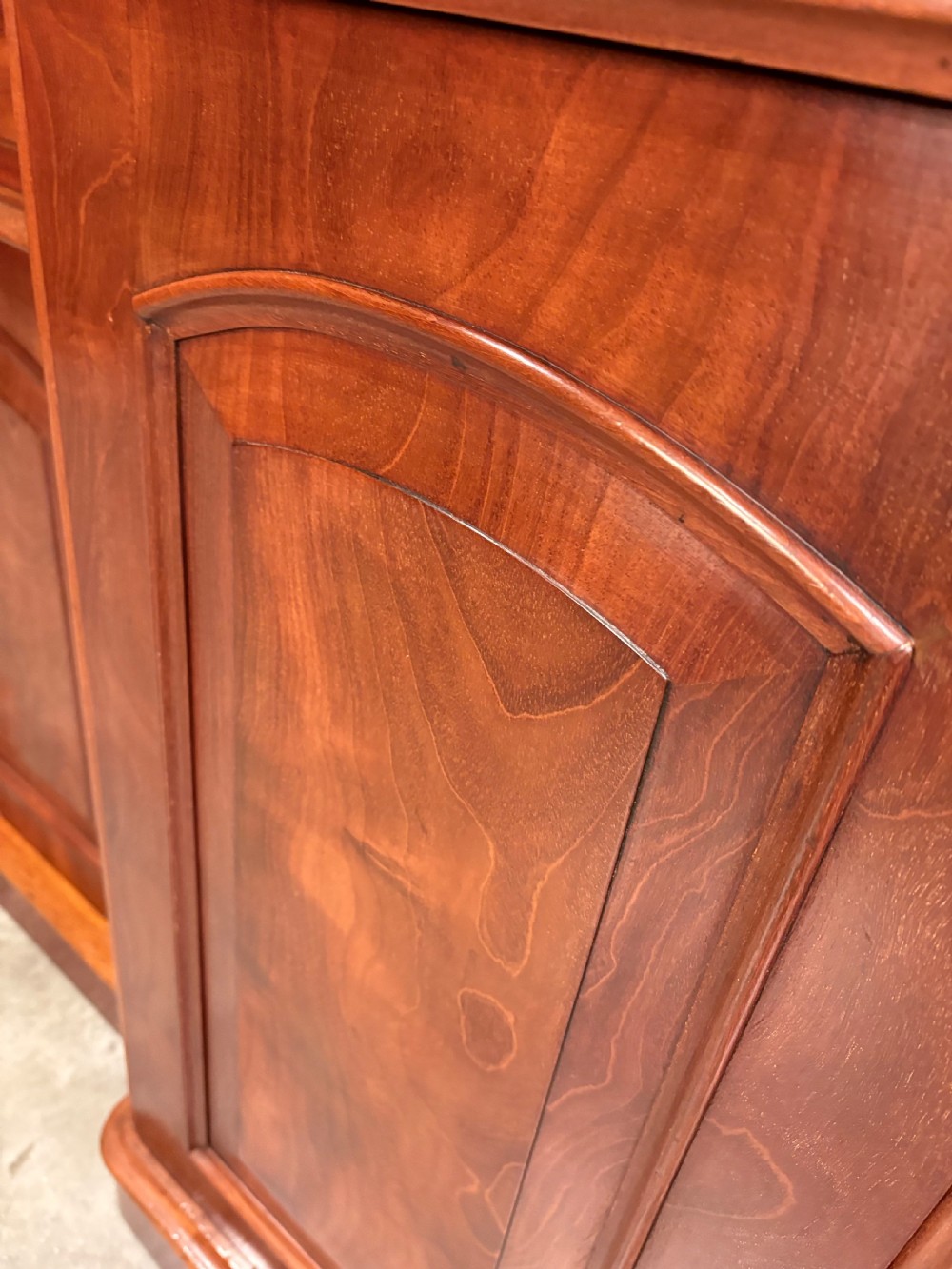 A Victorian mahogany three-door sideboard featuring flame mahogany panelled cupboard doors and a central top drawer on a solid plinth base. View XI