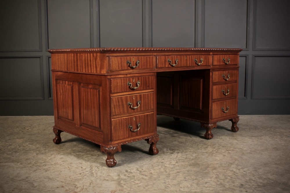 A mahogany pedestal desk with a brown leather inset writing surface, swan-neck brass handles, and carved claw and ball feet. View II