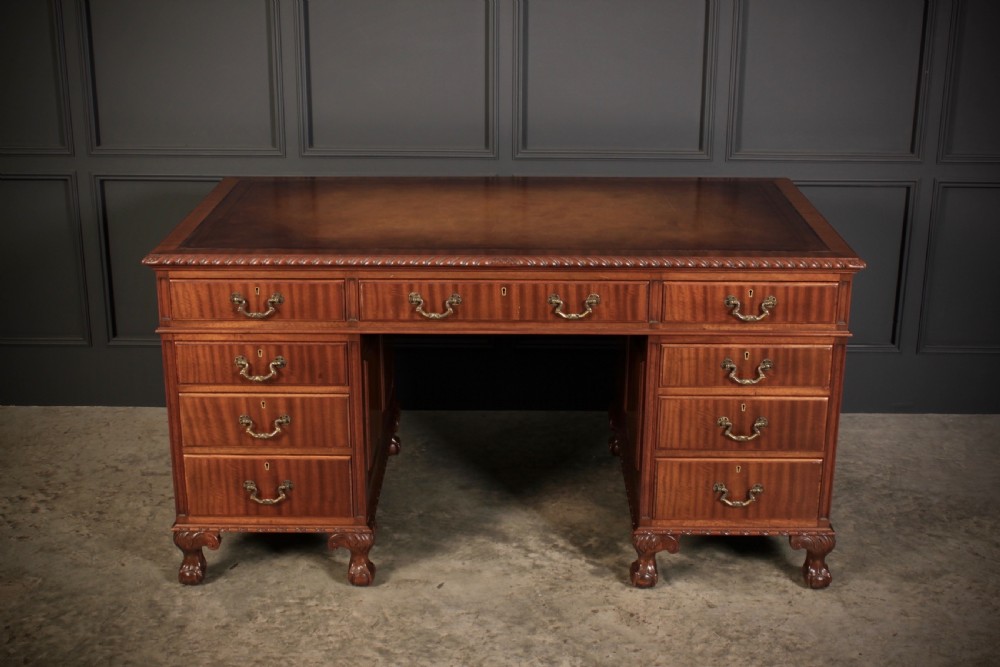 A mahogany pedestal desk with a brown leather inset writing surface, swan-neck brass handles, and carved claw and ball feet. View III