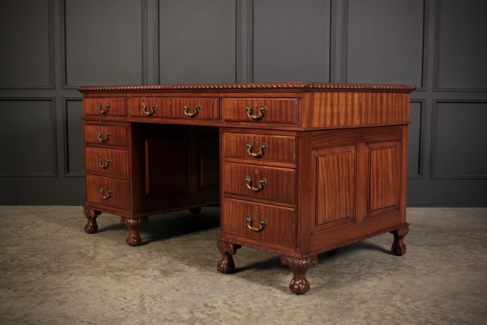 A mahogany pedestal desk with a brown leather inset writing surface, swan-neck brass handles, and carved claw and ball feet. View IV