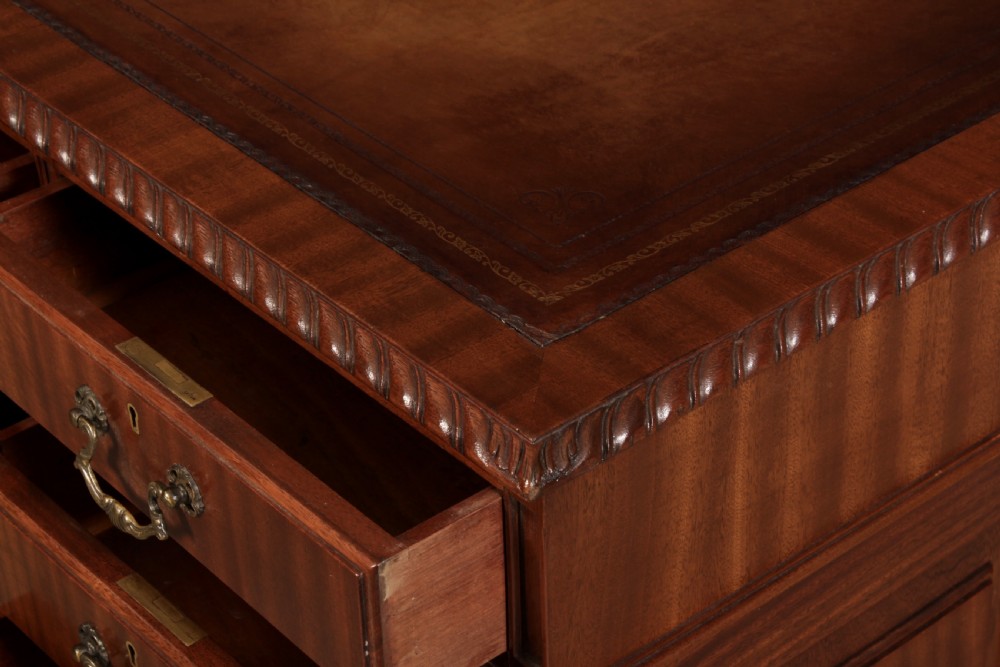 A mahogany pedestal desk with a brown leather inset writing surface, swan-neck brass handles, and carved claw and ball feet. View IX