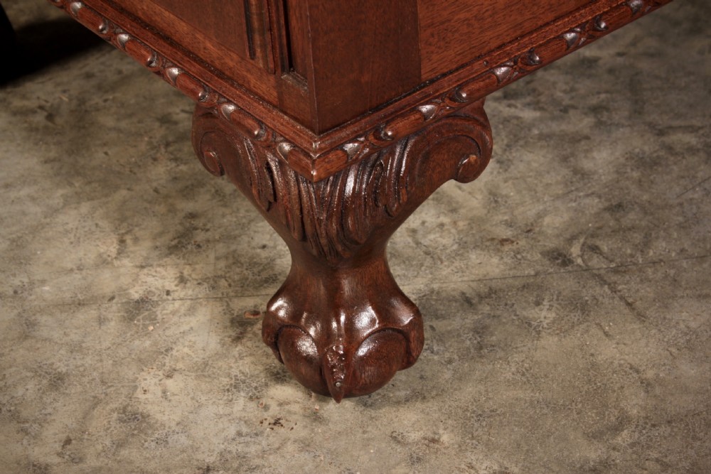 A mahogany pedestal desk with a brown leather inset writing surface, swan-neck brass handles, and carved claw and ball feet. View X