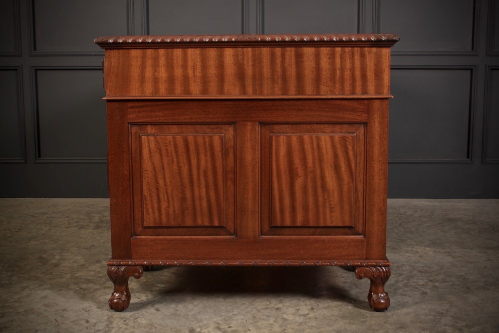 A mahogany pedestal desk with a brown leather inset writing surface, swan-neck brass handles, and carved claw and ball feet. View XI
