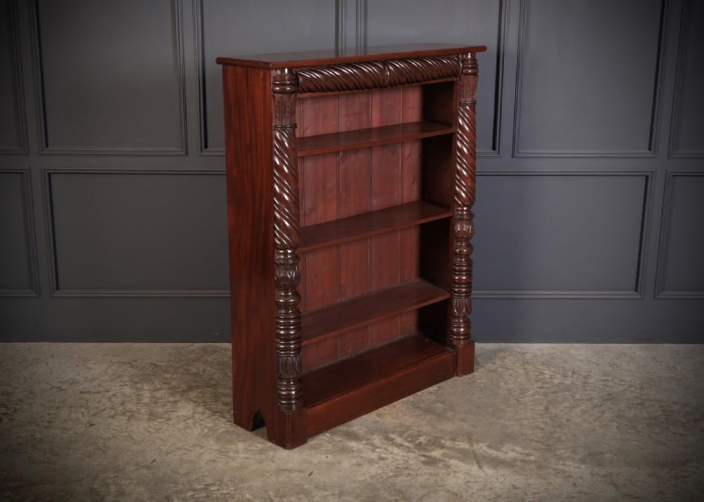 A William IV dark mahogany open bookcase featuring four shelves flanked by spiral twist carved columns and a detailed frieze.