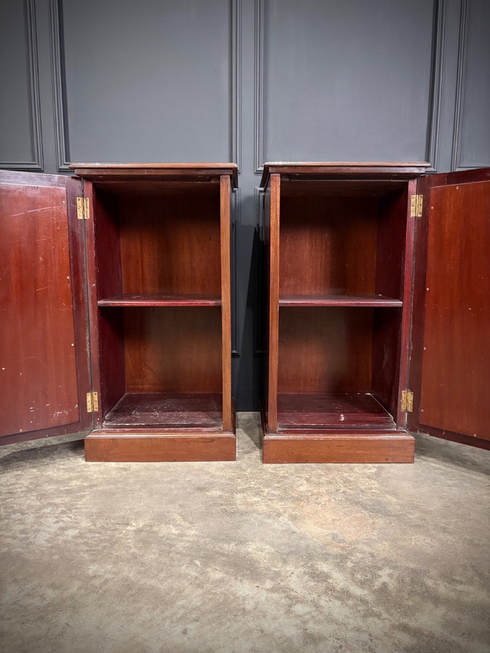 A pair of antique rich mahogany bedside cabinets featuring single arched panel doors and solid plinth bases. View XII