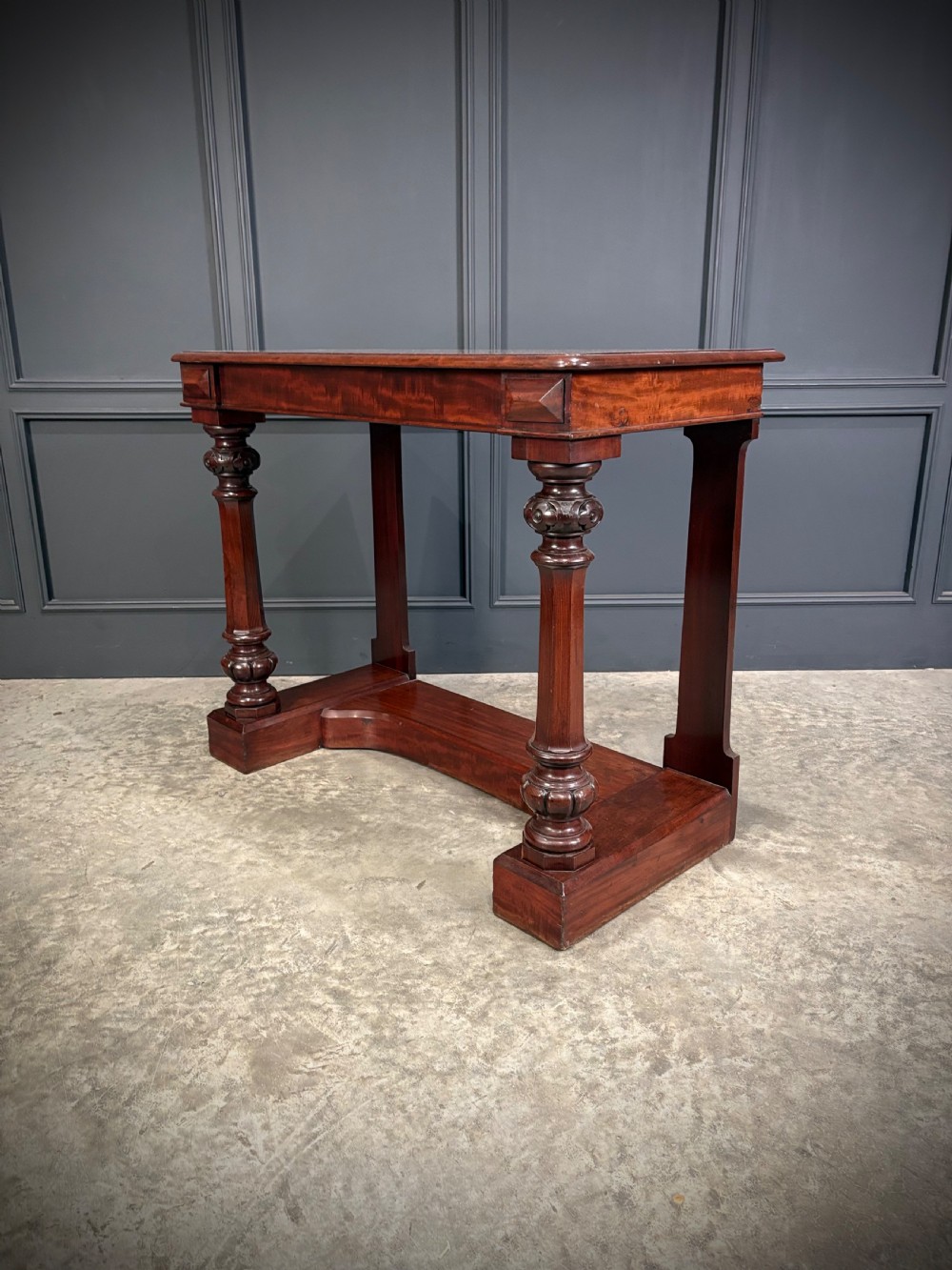 An antique dark mahogany console table featuring carved turned columns and a solid plinth base. View IX