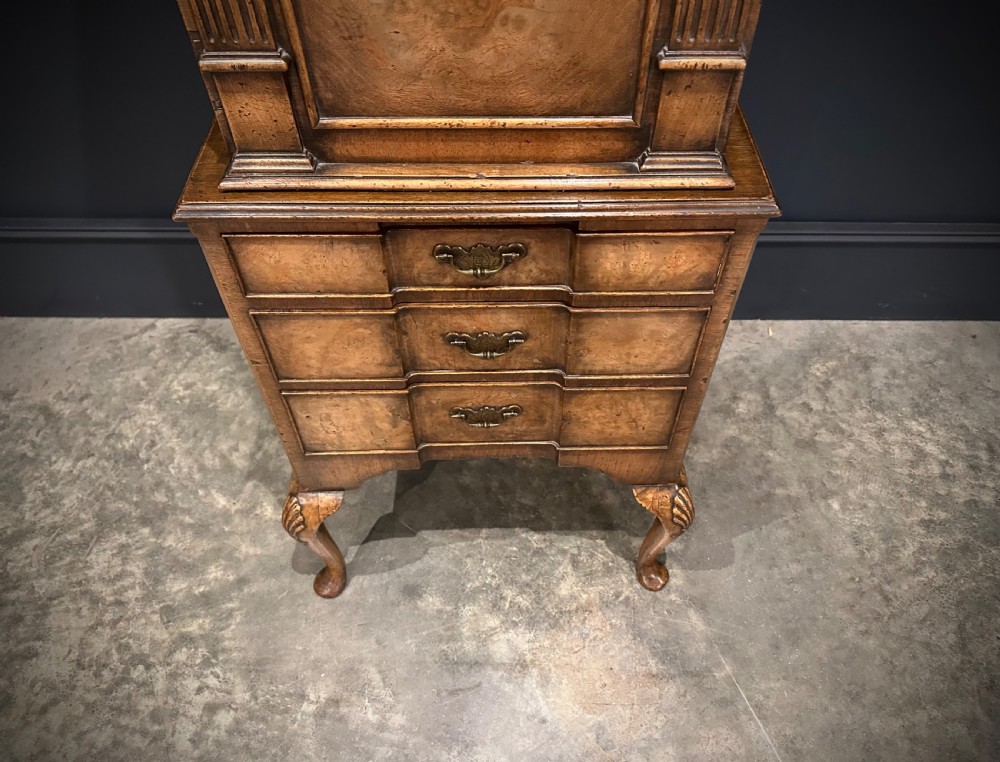 A tall, narrow Queen Anne style walnut bookcase featuring an arched burr walnut front panel, open side shelving, three drawers with brass handles, and cabriole legs with carved shell knees. View III