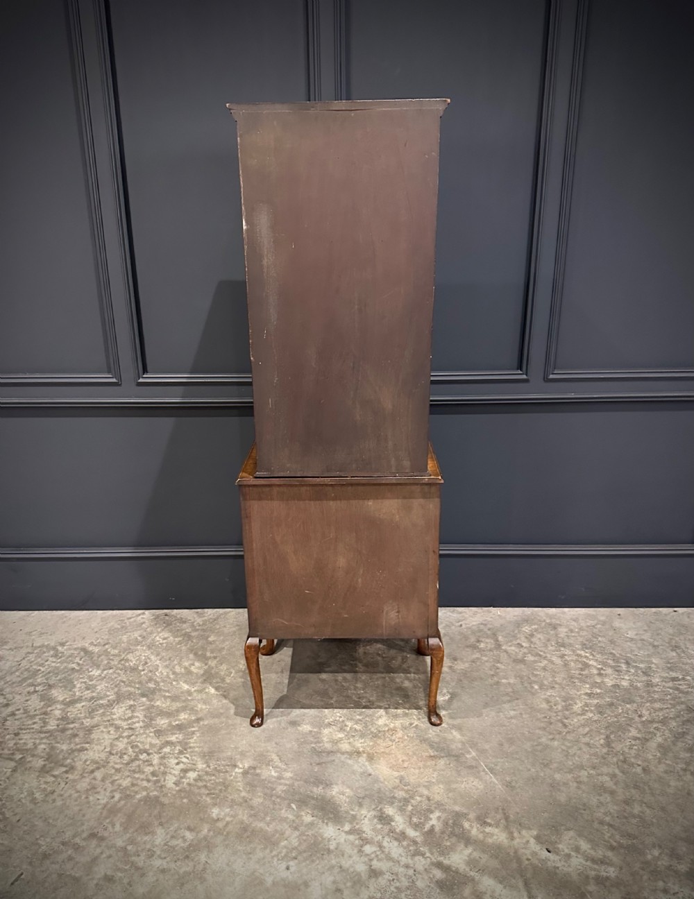A tall, narrow Queen Anne style walnut bookcase featuring an arched burr walnut front panel, open side shelving, three drawers with brass handles, and cabriole legs with carved shell knees. View XI