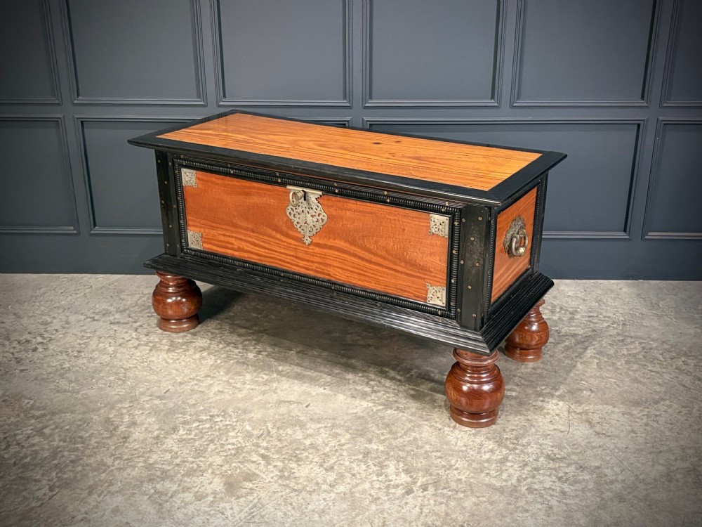 A large Ceylonese camphor wood and ebony storage trunk with an ornate metal escutcheon, side handles, and heavy turned bulbous feet. View XI