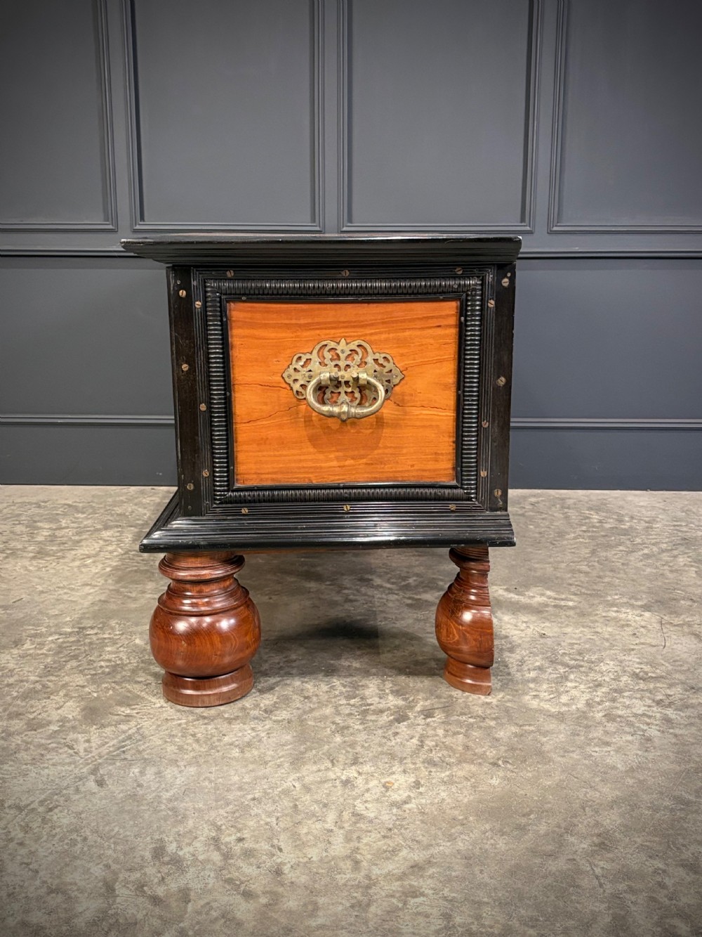 A large Ceylonese camphor wood and ebony storage trunk with an ornate metal escutcheon, side handles, and heavy turned bulbous feet. View XII