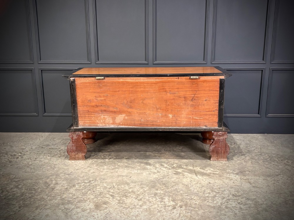 A large Ceylonese camphor wood and ebony storage trunk with an ornate metal escutcheon, side handles, and heavy turned bulbous feet. View XIII