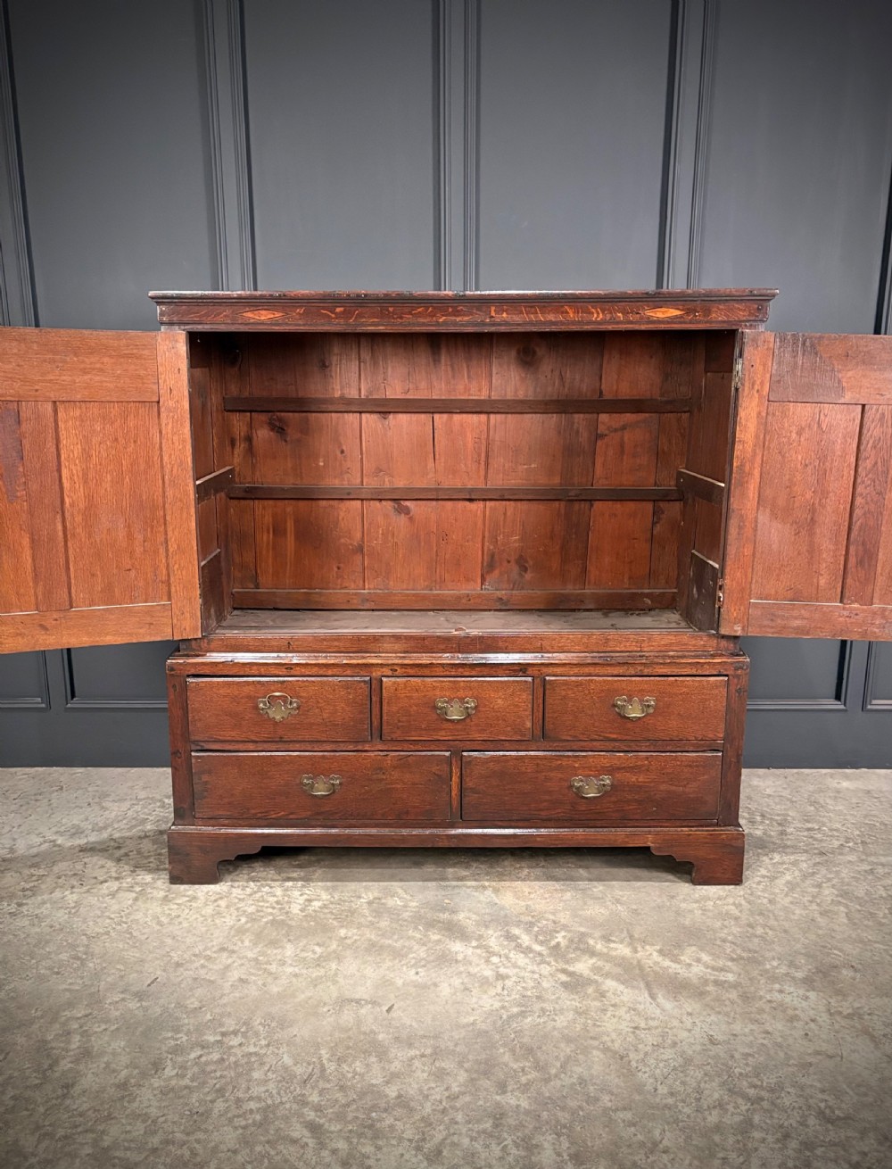 An 18th-century dwarf oak housekeepers cupboard featuring twin doors with pointed arch fielded panels over a base of five drawers. View IV