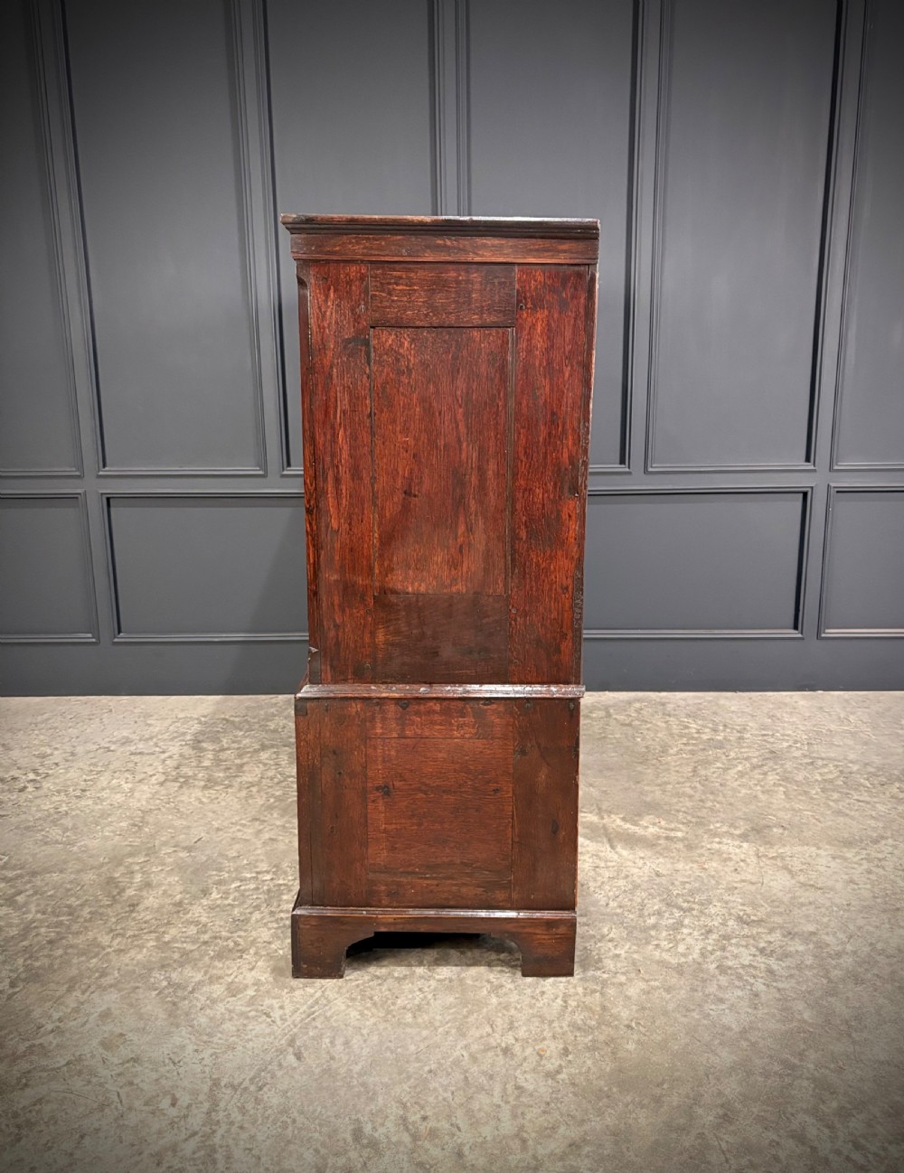 An 18th-century dwarf oak housekeepers cupboard featuring twin doors with pointed arch fielded panels over a base of five drawers. View VI