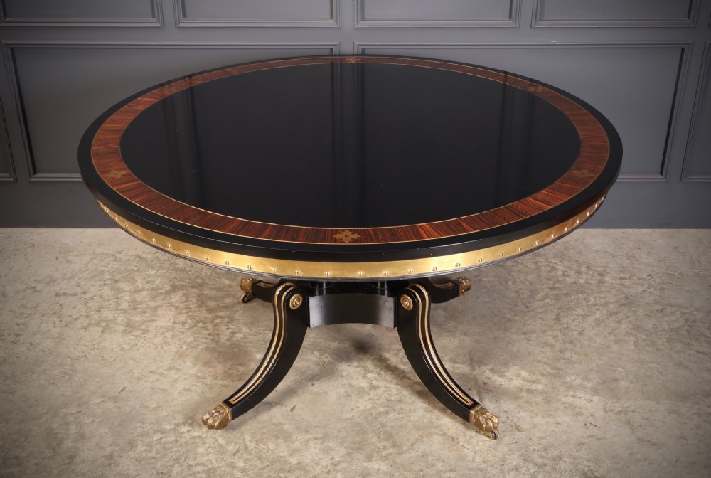 A circular ebonised centre table featuring brass line inlays, a crossbanded top border, a brass apron rim, and a quadruped pedestal base with brass lion paw feet. View III