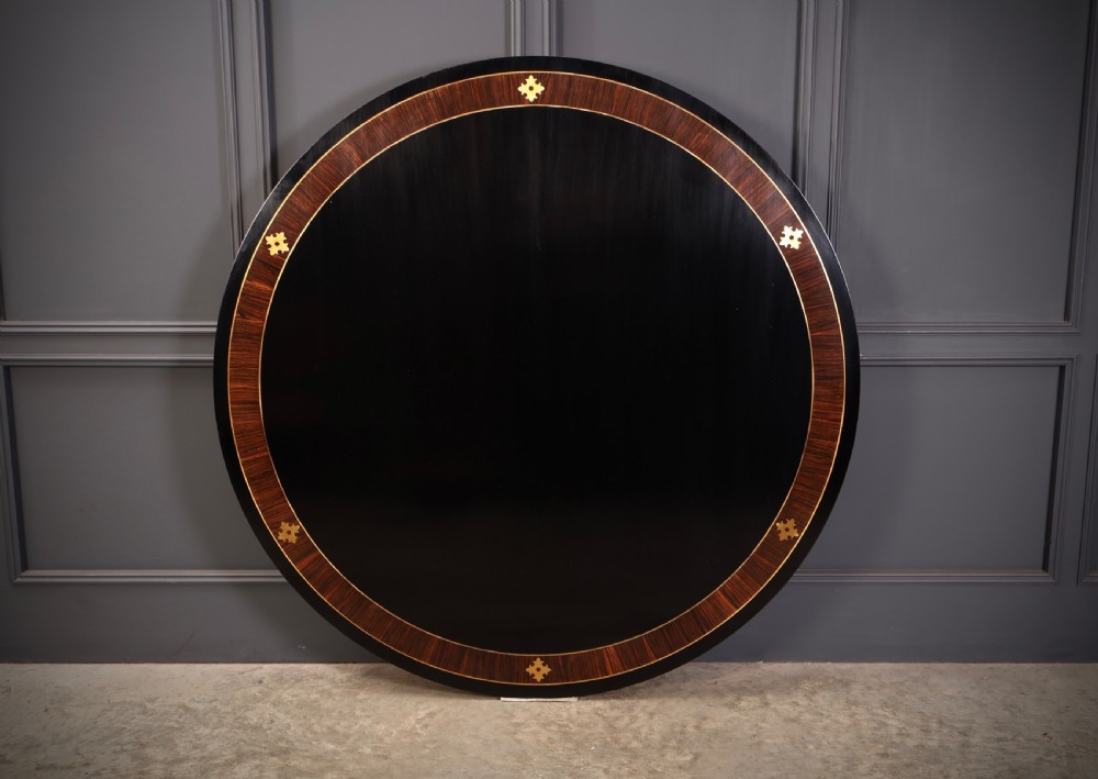 A circular ebonised centre table featuring brass line inlays, a crossbanded top border, a brass apron rim, and a quadruped pedestal base with brass lion paw feet. View VI