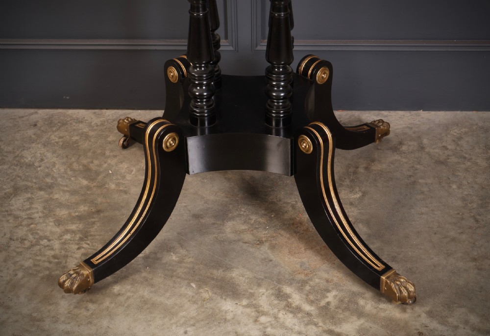 A circular ebonised centre table featuring brass line inlays, a crossbanded top border, a brass apron rim, and a quadruped pedestal base with brass lion paw feet. View X