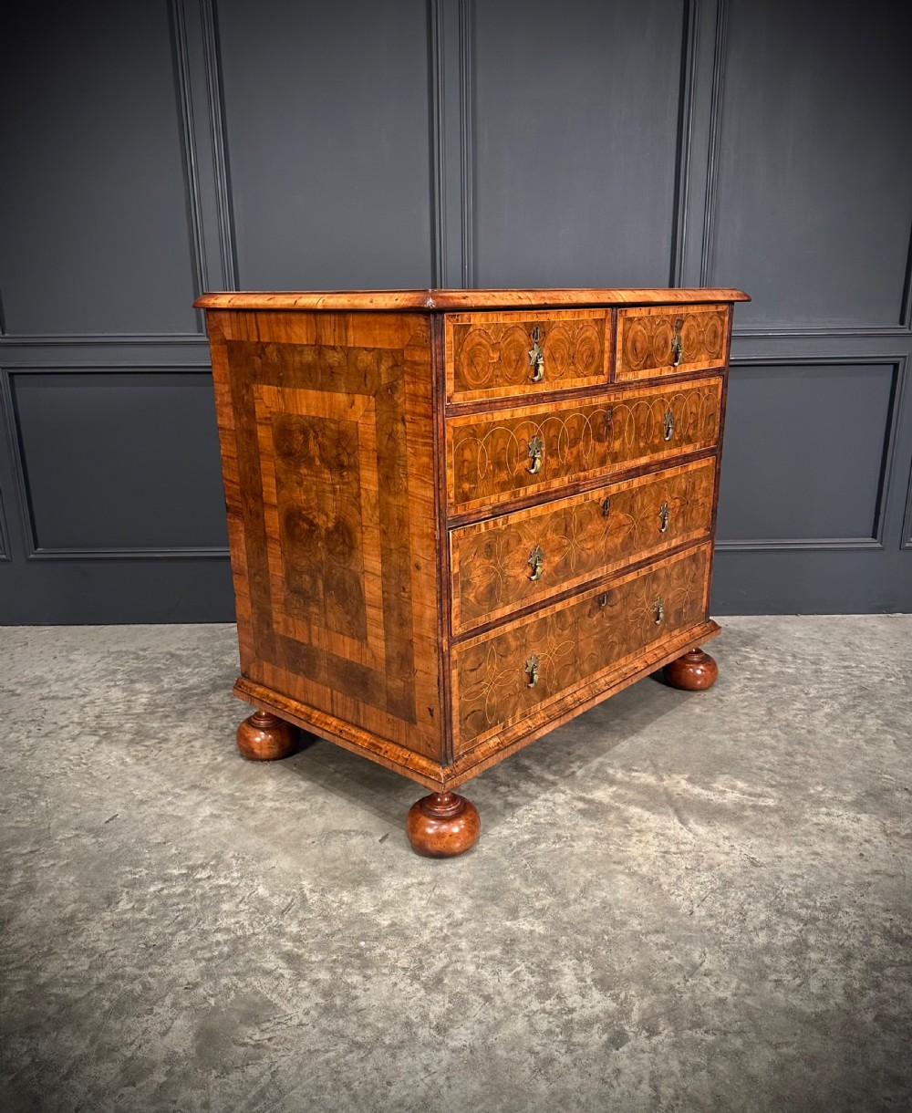 A William and Mary period walnut chest of drawers featuring geometric oyster veneering, brass teardrop handles, and turned bun feet. View III