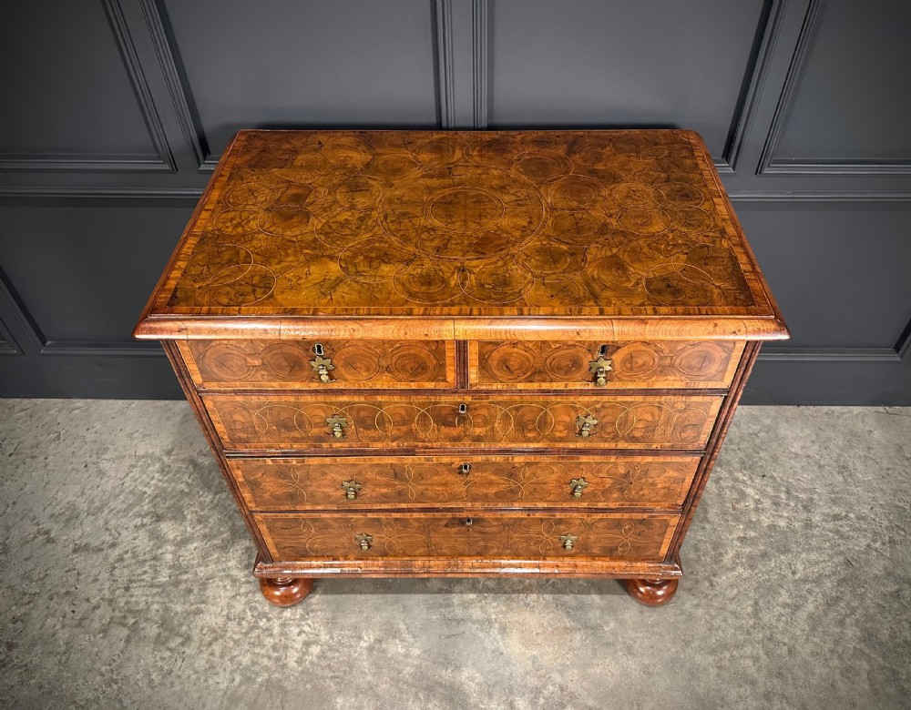 A William and Mary period walnut chest of drawers featuring geometric oyster veneering, brass teardrop handles, and turned bun feet. View IV