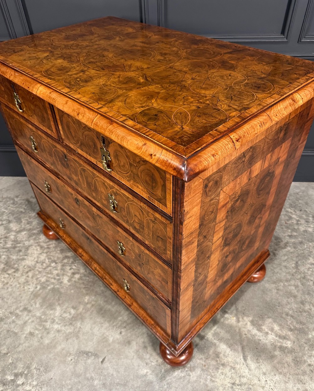 A William and Mary period walnut chest of drawers featuring geometric oyster veneering, brass teardrop handles, and turned bun feet. View XI