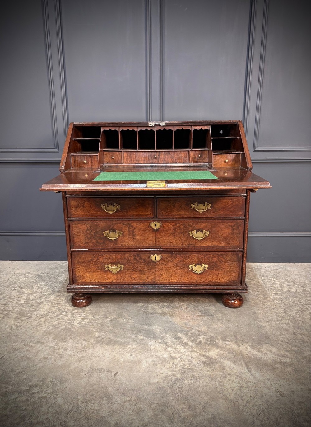 An antique Queen Anne walnut bureau featuring a sloping write-down front above drawers with brass handles, raised on compressed bun feet. View III