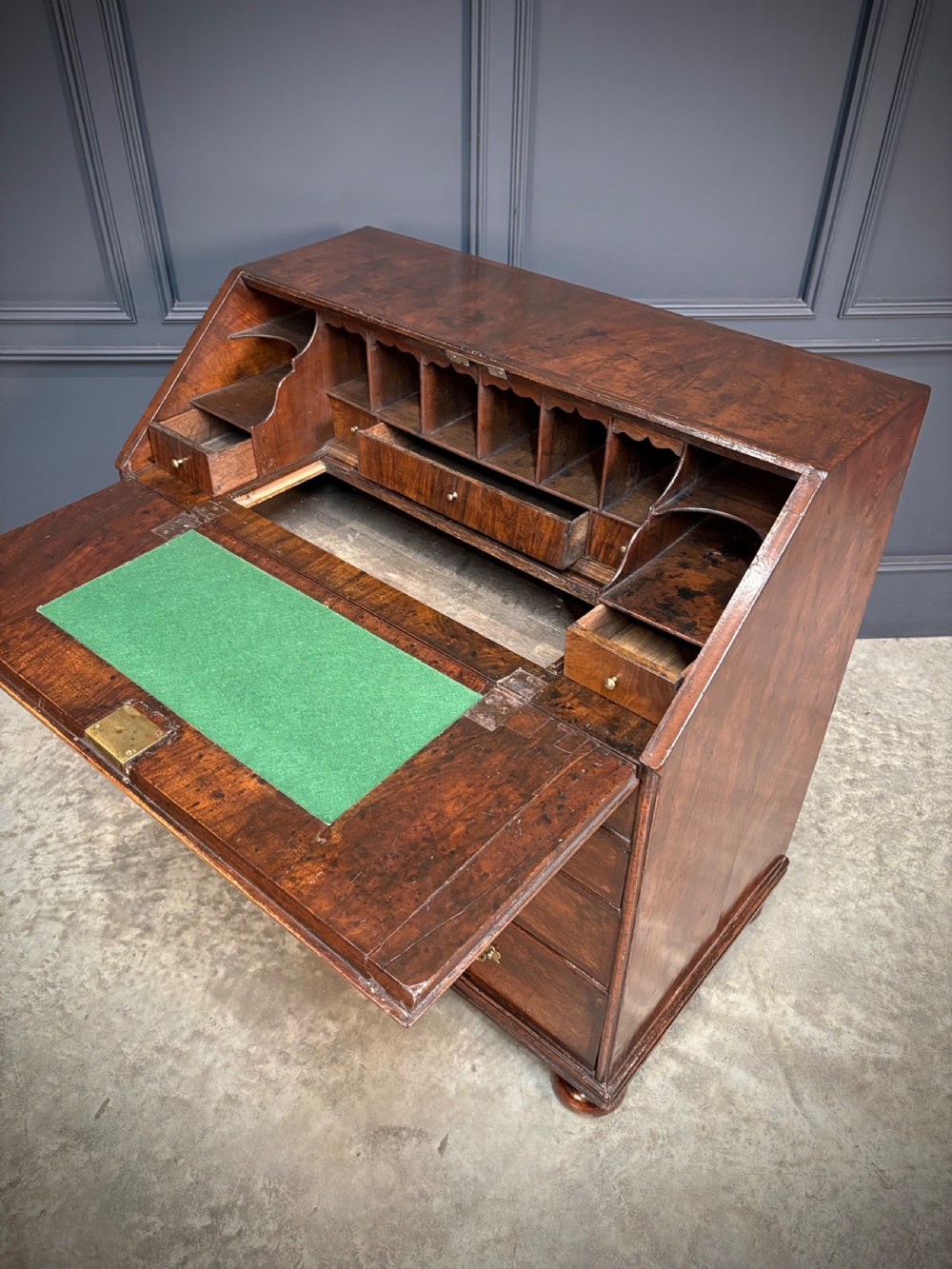 An antique Queen Anne walnut bureau featuring a sloping write-down front above drawers with brass handles, raised on compressed bun feet. View IX