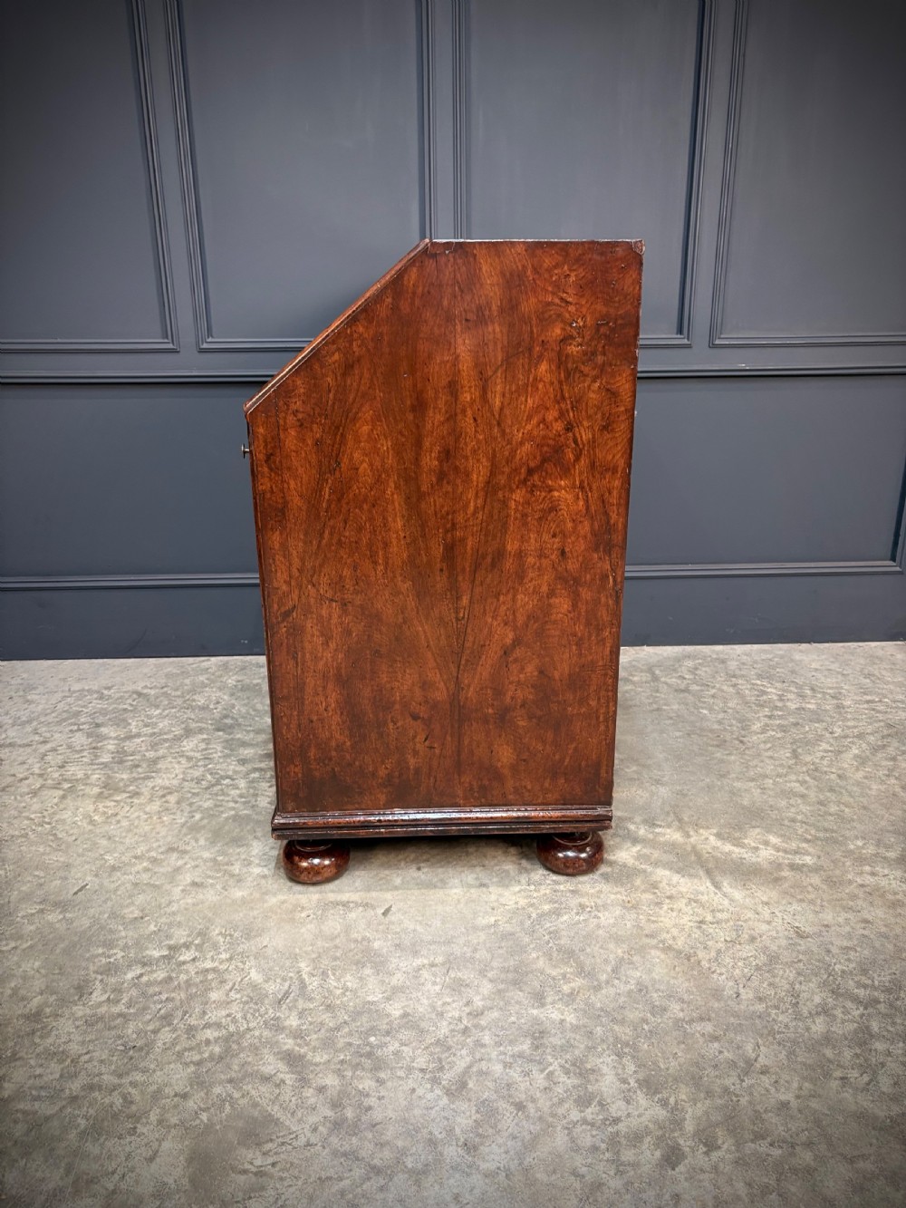 An antique Queen Anne walnut bureau featuring a sloping write-down front above drawers with brass handles, raised on compressed bun feet. View X