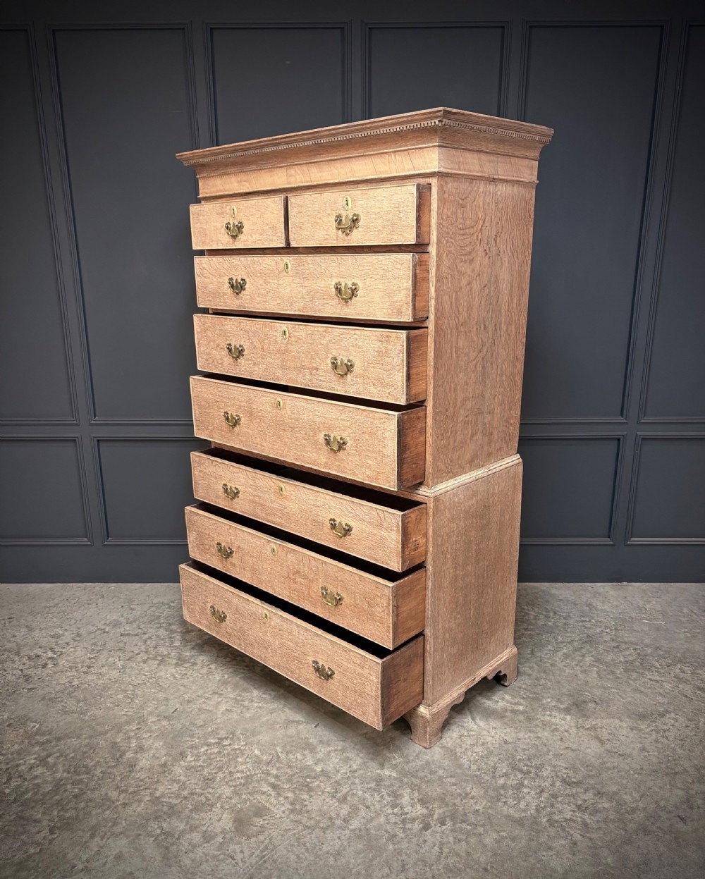 An 18th-century bleached oak chest on chest with stacked upper and lower drawer sections, brass drop handles, and bracket feet. View V