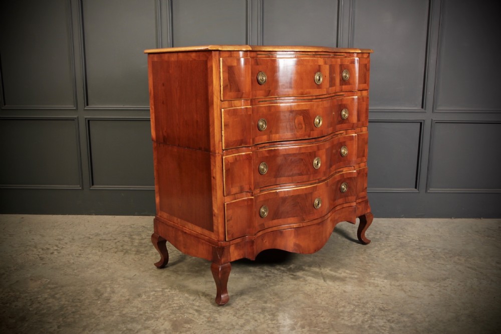 An antique walnut serpentine-front chest featuring four drawers with brass ring pull handles resting on carved cabriole feet. View II