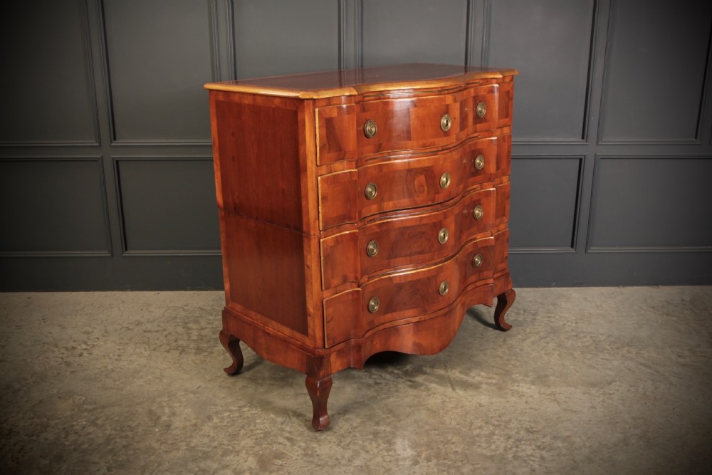 An antique walnut serpentine-front chest featuring four drawers with brass ring pull handles resting on carved cabriole feet. View III