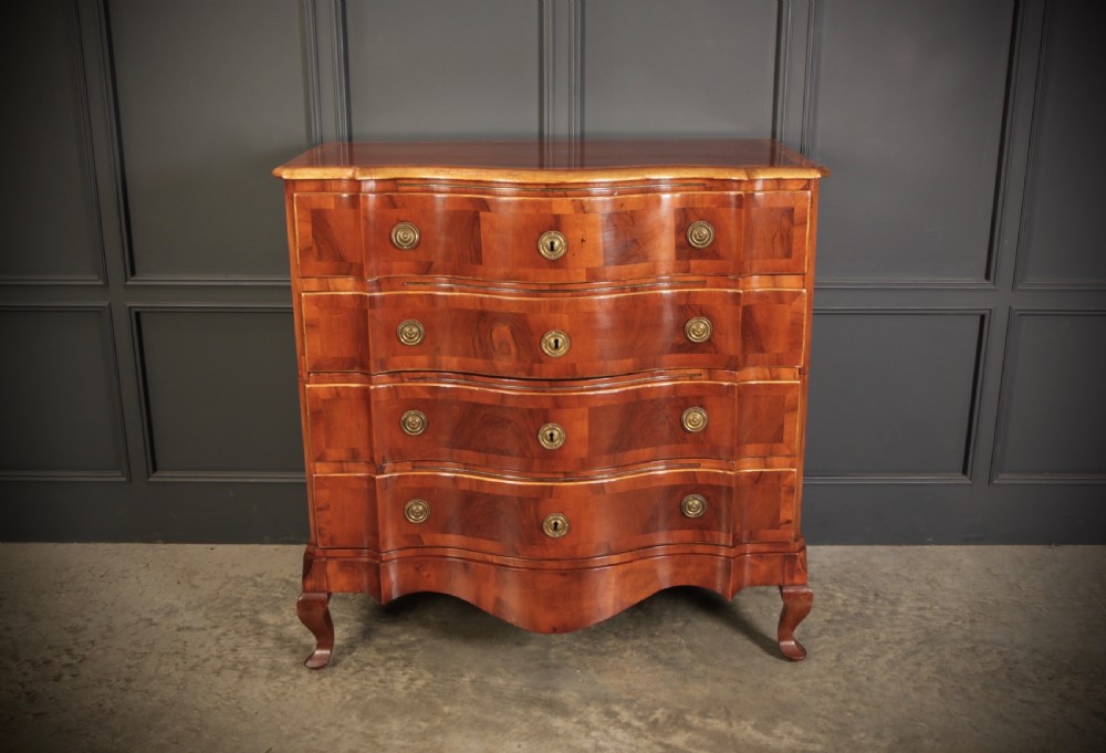 An antique walnut serpentine-front chest featuring four drawers with brass ring pull handles resting on carved cabriole feet. View IV