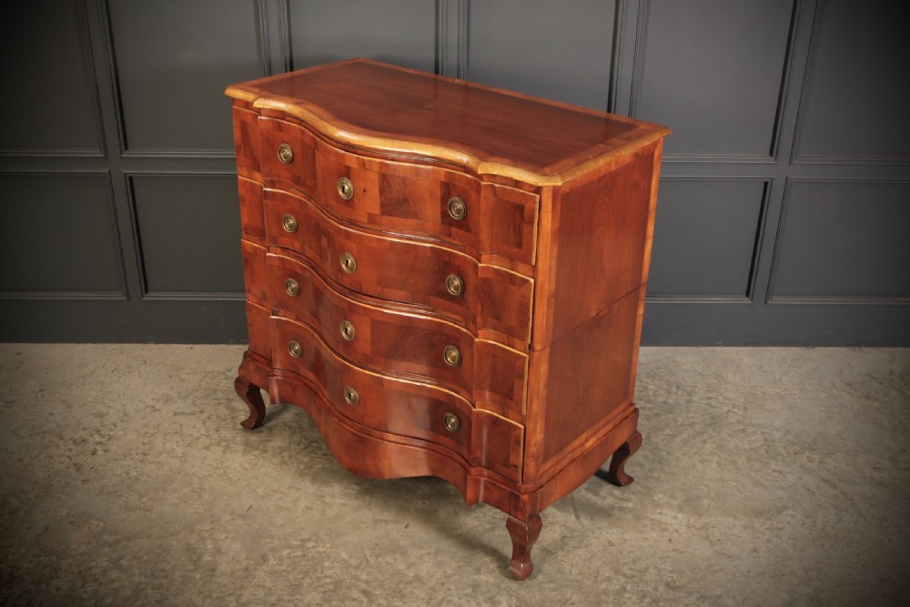 An antique walnut serpentine-front chest featuring four drawers with brass ring pull handles resting on carved cabriole feet. View VI