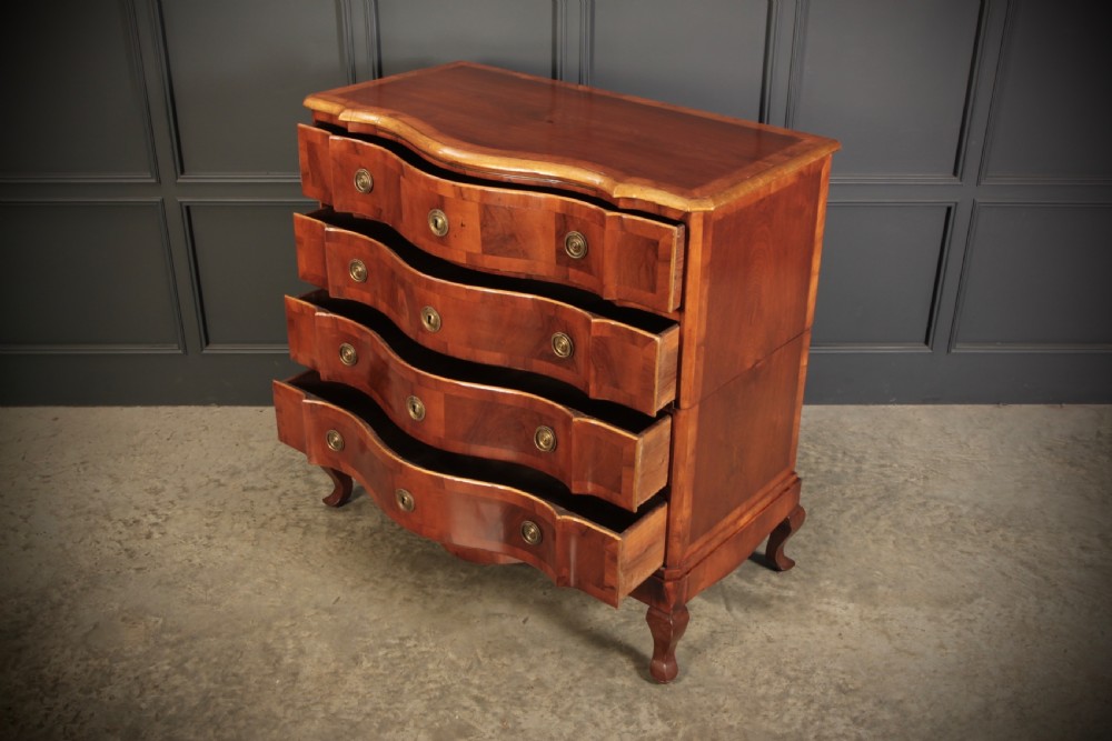 An antique walnut serpentine-front chest featuring four drawers with brass ring pull handles resting on carved cabriole feet. View VII