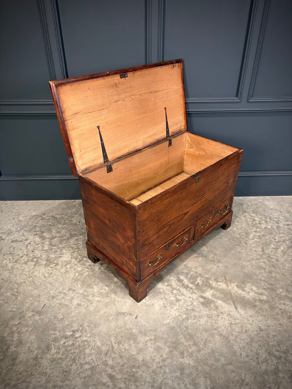 A Georgian elm blanket box featuring a hinged top lid, two lower drawers with brass swan-neck handles, and shaped bracket feet. View III