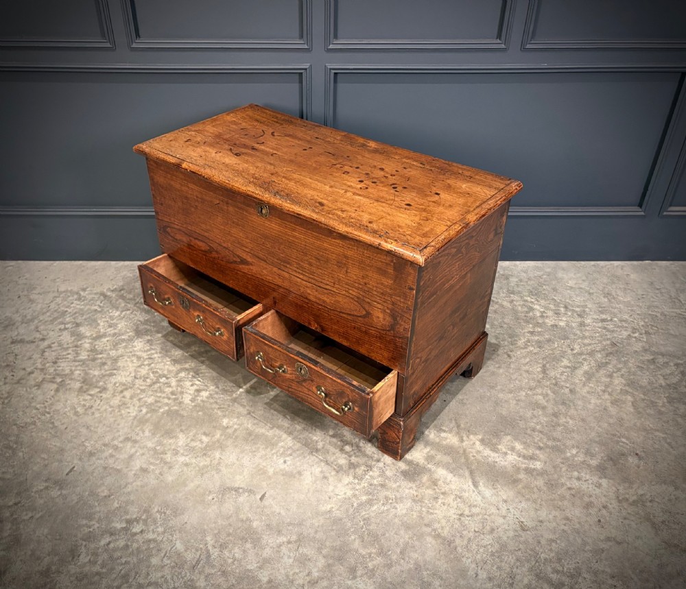 A Georgian elm blanket box featuring a hinged top lid, two lower drawers with brass swan-neck handles, and shaped bracket feet. View VIII